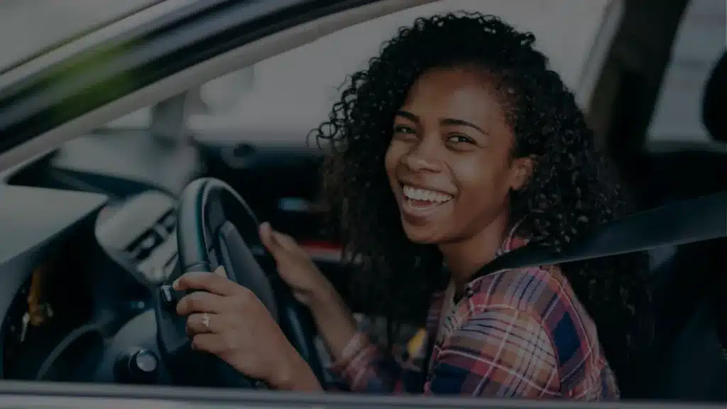 Gelukkige vrouw achter het stuur tijdens rijles bij Rijschool Welslagen Rotterdam