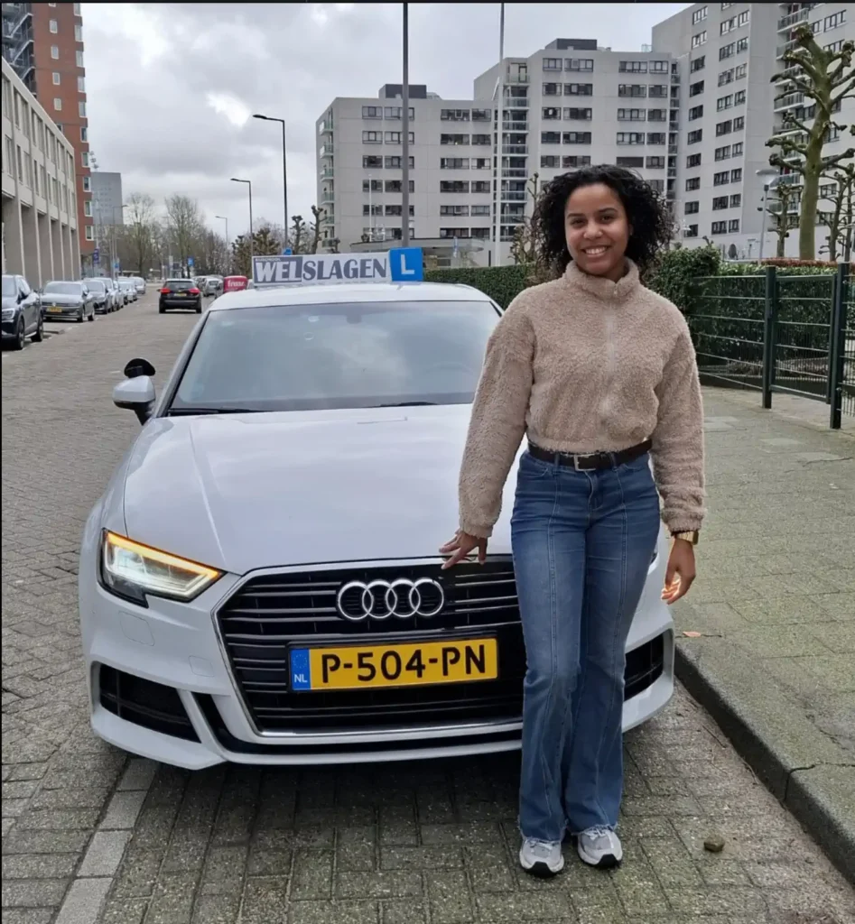 Geslaagde leerling poseert trots naast witte Audi lesauto van Rijschool Welslagen in Rotterdam