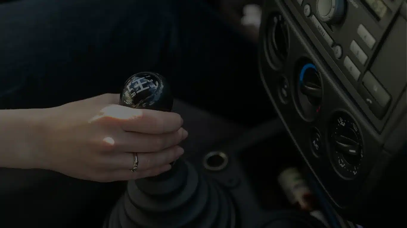 Hand op versnellingspook in auto-interieur tijdens rijles