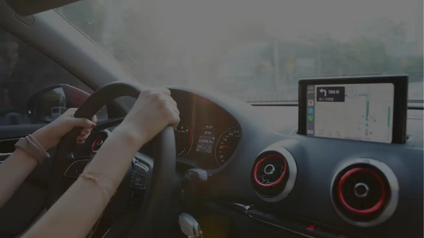 Student houdt stuur vast tijdens rijles in auto met navigatiesysteem en moderne dashboard